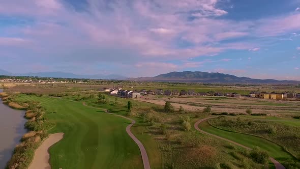 Aerial view of a golf course, river, sand traps, greens and people playing