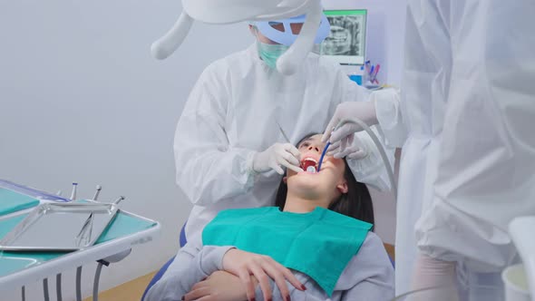 Asian dentist wear PPE use suction dry mouth during treatment procedures for oral care in clinic.