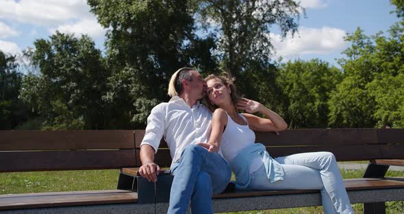 Love and Relationships  a Man Kisses a Woman During a Romantic Walk in the Park