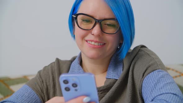 White nerdy girl in glasses using modern smartphone for communication online in 4k video