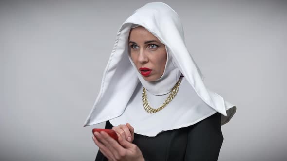 Positive Woman in Nun Costume Showing I Got an Idea Gesture Texting on Smartphone