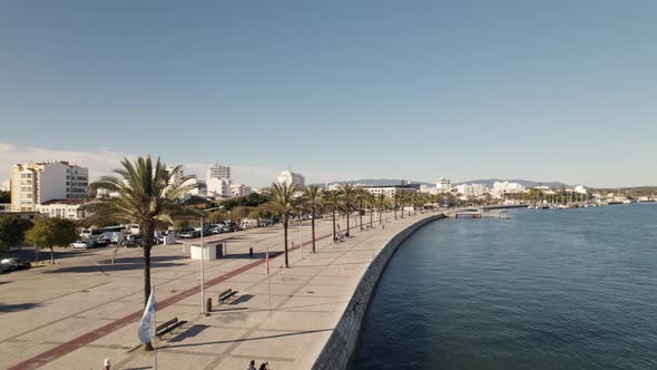 Aerial pullback Reveal Scenic Promenade riverside with palm trees, Portimão - Algarve