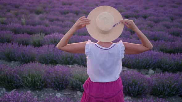 Woman in a Short Purple Dress and a Hat Stands on a Lavender Field