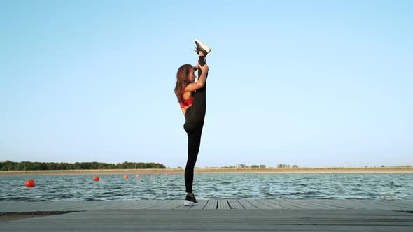 young athletic Caucasian girl in a red tank top and leggings shows her stretch and flexibility