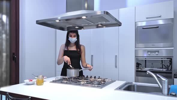 Young woman cooking food for delivery in protective mask.
