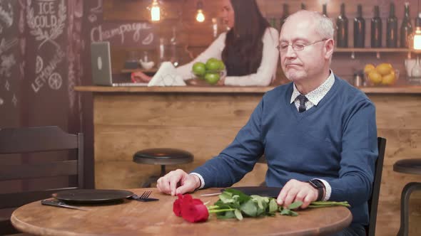 Sad Old Man Sitting at a Table in a Restaurant and Waiting for His Date