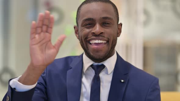 Portrait of Cheerful African Businessman Waving at the Camera 