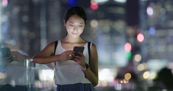 Woman use of smart phone in city at night