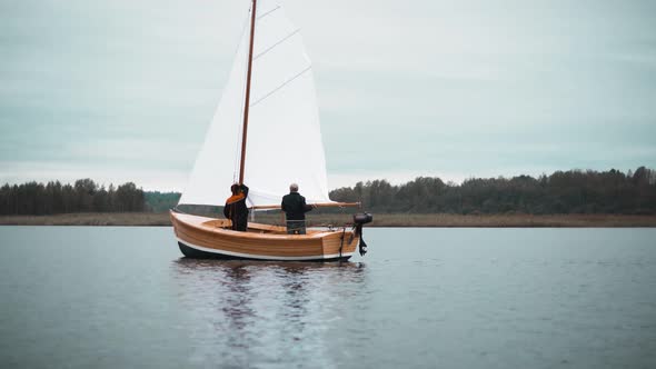 Wood Sailboat with Two Men Trying To Set Mast