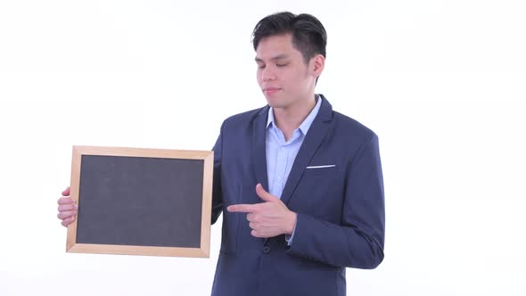 Stressed Young Asian Businessman Holding Blackboard and Giving Thumbs Down