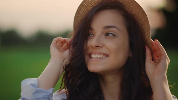 Smiling Woman Wearing Straw Hat Outdoors. Portrait of Joyful Lady in Park