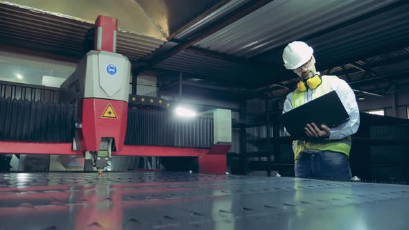 Factory Inspector Is Looking at the Laser Equipment Cutting Metal