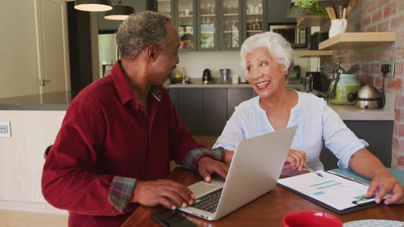 Senior African American husband and mixed race wife happily working on a laptop at home