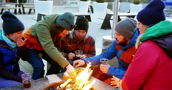 Friends having snacks near campfire