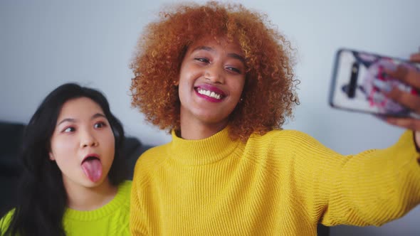 Best Friends Asian and African American Black Woman Taking Selfie Using Smartphone. Funny Faces