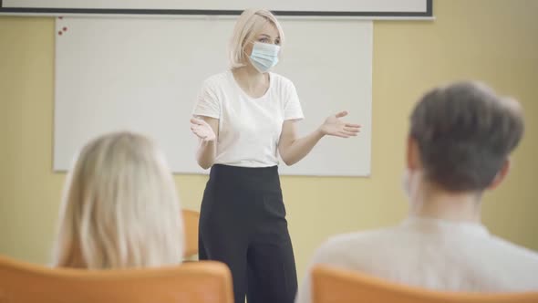 Female Lecturer in Covid Face Mask Talking To People in Auditorium