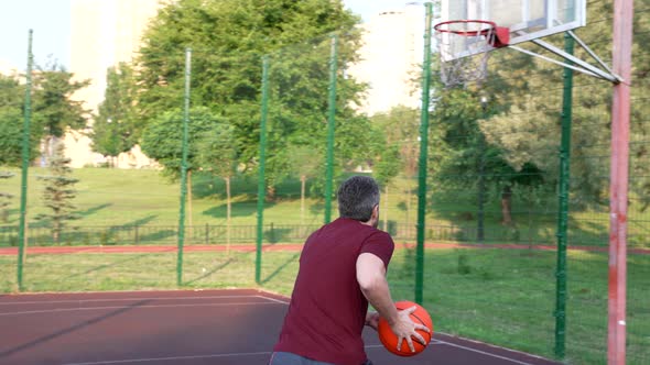 Man Playing Basketball Throwing Ball Into Basket on Playground Sport