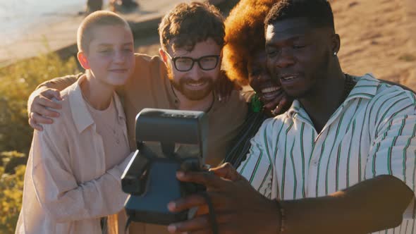 Multiethnic Group of Best Friends Creating Memories By Taking Funny Photos with a Vintage Polaroid