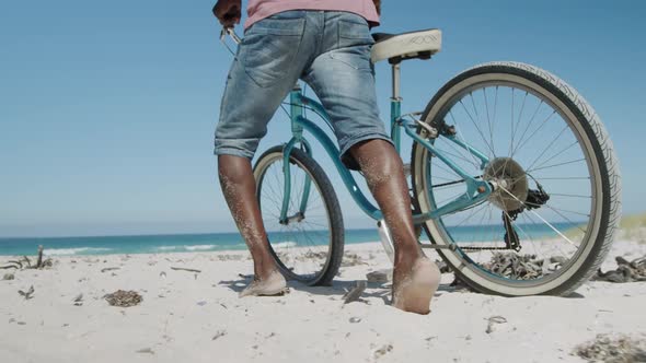 Senior couple walking with a bike at the beach