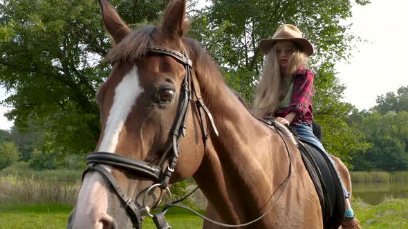 Young Cowgirl in Hat Riding Her Horse