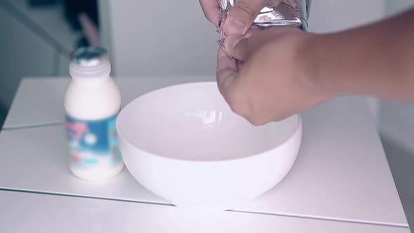 Man Prepares Breakfast and Pours Honey Cereals Into Bowl