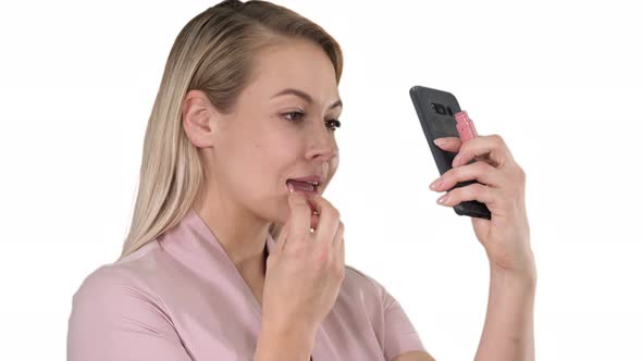 Beautiful Young Blonde Woman Which Is Painting Her Lips with Red Lipstick and Looking in the Phone