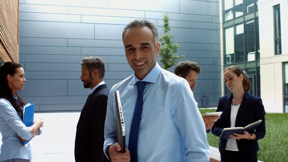 Smiling businessman holding laptop