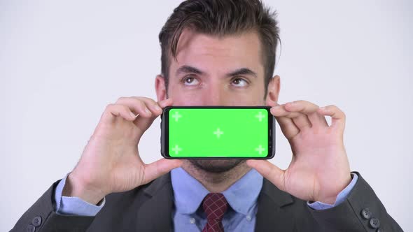 Young Handsome Hispanic Businessman Thinking While Showing Phone