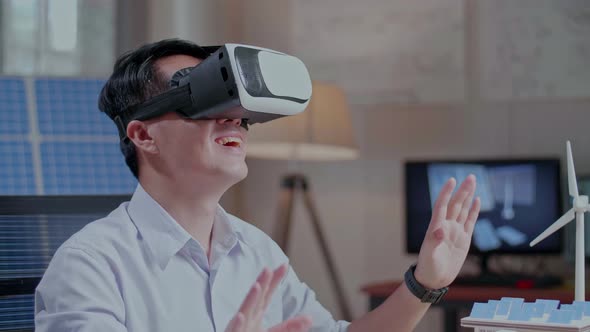 Asian Man Working With A Model Of Small House Roof Solar Panel Wearing Vr And Touching Gesture