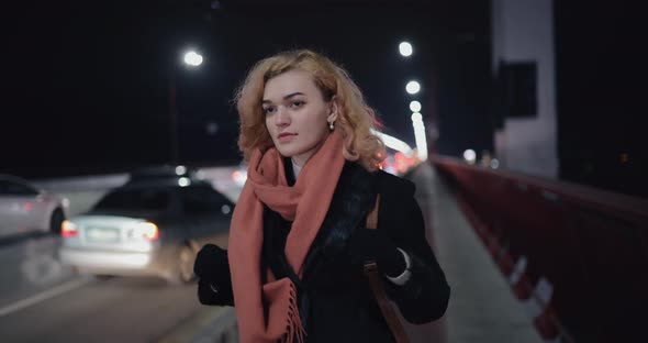 Dreamy Woman Walks in the Evening Across the Bridge Near the Cars in Thought