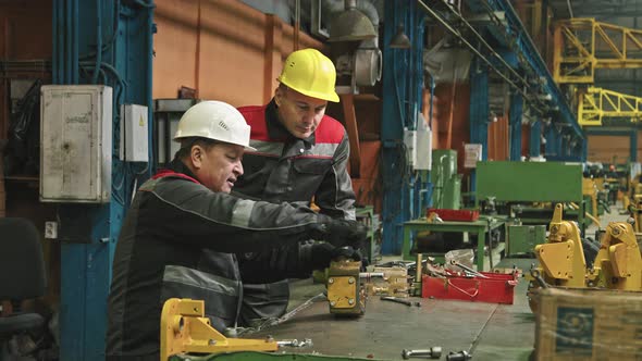 Male Workers Assembling Machinery With Wrench