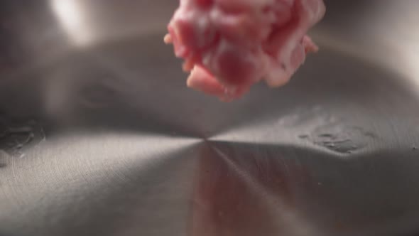 Camera follows cooking bacon in a pan. Slow Motion.