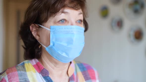 coronavirus pandemic. elderly woman in a medical mask looks at the light