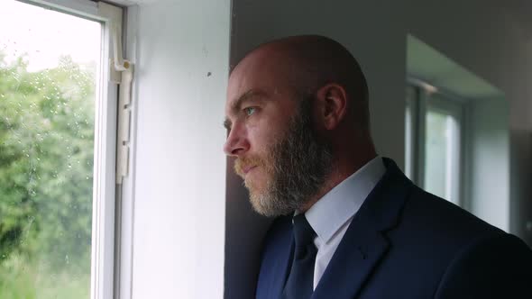 Portrait of a pensive businessman looking out of a window at the rain