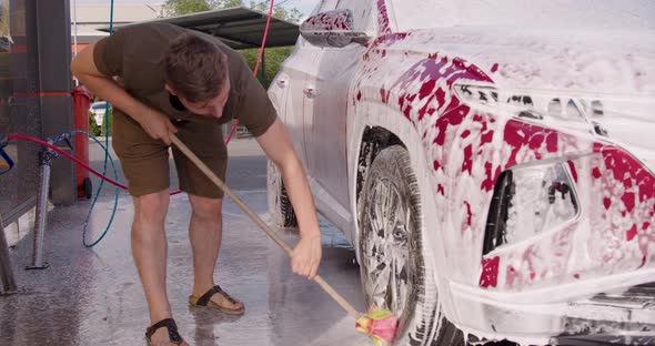 Man Washing Her Car in a Self Service Car Wash Station