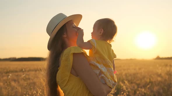 A Happy Mom with A Little Girl on Shoulders and Walking at Meadow on Sunny Summer Day