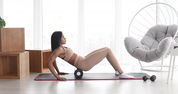 Fitness black woman in sportswear doing fitness using foam roller.