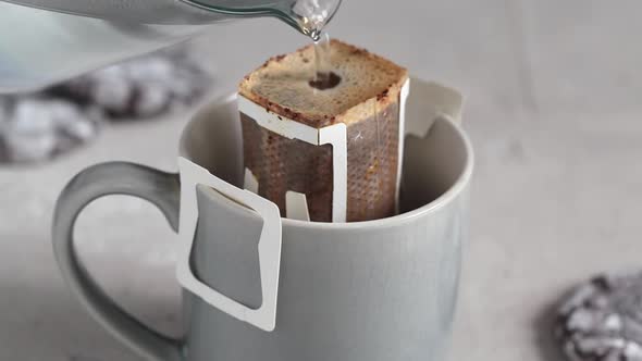 Making coffee with drip coffee bag in gray cup.