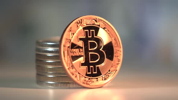 Gold Bitcoin BTC Rotate on the Table with Patch of Reflected Light. Many Other Crypto Coins on the