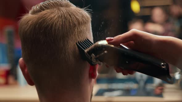 Barbershop: woman hairdresser cuts man's hair with a razor