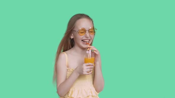 Laughing Happy Teen Girl in Glasses and Dress Drinking Juice on Green Screen