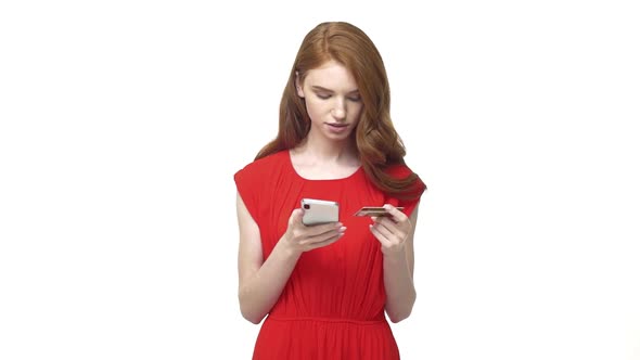 Young Woman Holding Her Credit Card About To Make An Online Shopping Purchase on Mobile Phone