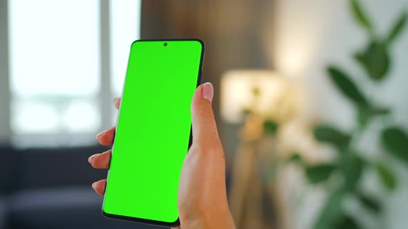 Woman at Home Using Smartphone with Green Mockup Screen in Vertical Mode