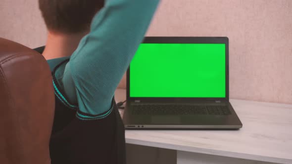 A Man Doing Warm Up Exercises While Sitting at a Laptop Via Video Call in a Protective Face Mask