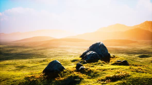 Meadow with Huge Stones Among the Grass on the Hillside at Sunset