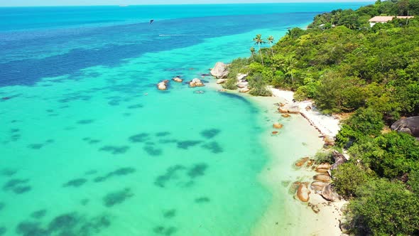 Parasailing over beautiful tranquil lagoon with coral reefs underwater, exotic beach with white sand