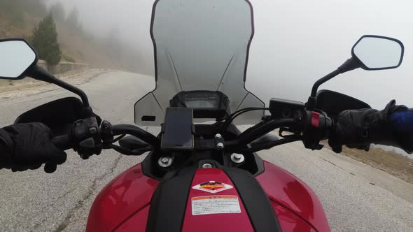POV Biker on Motorcycle Rides on High Mountain Pass in Cloudy Weather with Fog