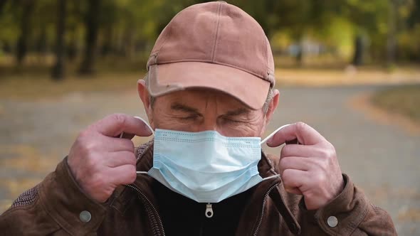 Close Up Portrait Elderly Man Puts a Medical Mask on His Face