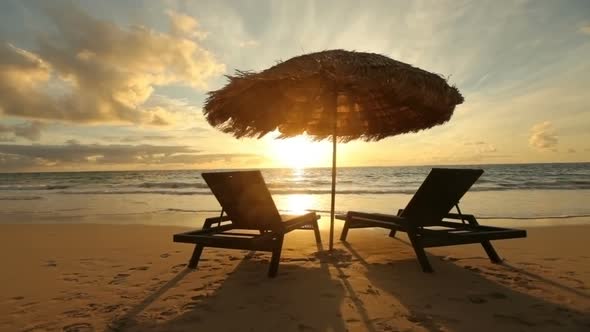 Sunrise at tropical beach with chairs and hut