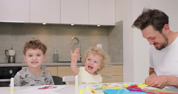 Small Girl and a Small Boy are Showing Their Hands to the Camera and are Smilign While Their Father